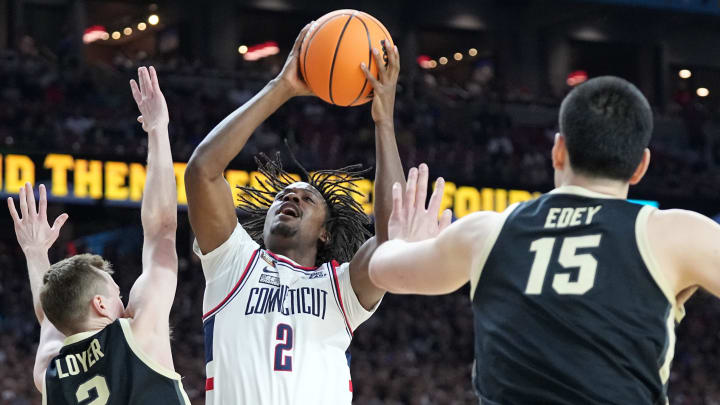 Connecticut Huskies guard Tristen Newton (2) shoots the ball past Purdue Boilermakers guard Fletcher Loyer (2) and Purdue Boilermakers center Zach Edey (15) during the NCAA Men’s Basketball Tournament Championship, Monday, April 8, 2024, at State Farm Stadium in Glendale, Ariz.