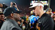Nov 29, 2025; Los Angeles, California, USA; UCLA Bruins interim coach Tim Skipper (left) shakes hands with Southern California Trojans head coach Lincoln Riley after the game at United Airlines Field at Los Angeles Memorial Coliseum. Mandatory Credit: Kirby Lee-Imagn Images