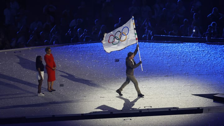 Aug 11, 2024; Saint-Denis, France; Gold medalist Simone Biles and Los Angeles Mayor Karen Bass hand the Olympic flag off to Tom Cruise during the closing ceremony for the Paris 2024 Olympic Summer Games at Stade de France.