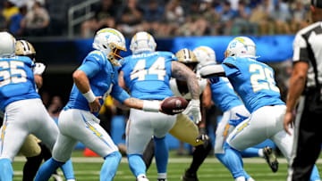 Aug 10, 2025; Inglewood, California, USA; Los Angeles Chargers quarterback Taylor Heinicke (4) hands off to running back Hassan Haskins (28) against the New Orleans Saints at SoFi Stadium. 