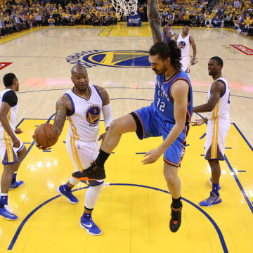 May 26, 2016; Oakland, CA, USA; Oklahoma City Thunder center Steven Adams (12) holds onto the rim after dunking the ball next to Golden State Warriors forward Marreese Speights (5) in the second quarter in game five of the Western conference finals of the NBA Playoffs at Oracle Arena. The Warriors won 120-111. 