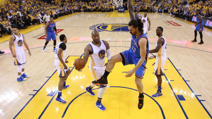 May 26, 2016; Oakland, CA, USA; Oklahoma City Thunder center Steven Adams (12) holds onto the rim after dunking the ball next to Golden State Warriors forward Marreese Speights (5) in the second quarter in game five of the Western conference finals of the NBA Playoffs at Oracle Arena. The Warriors won 120-111. 