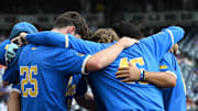 Jun 17, 2025; Omaha, Neb, USA;  UCLA Bruins players huddle before the restart of the game against the LSU Tigers at Charles Schwab Field. Mandatory Credit: Steven Branscombe-Imagn Images