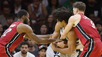 Nov 26, 2025; Miami, Florida, USA; Miami Heat guard Dru Smith (12) and guard Pelle Larsson (9) fight with Milwaukee Bucks center Jericho Sims (00) for a loose ball during the second half of an NBA Cup game at Kaseya Center. Mandatory Credit: Rhona Wise-Imagn Images