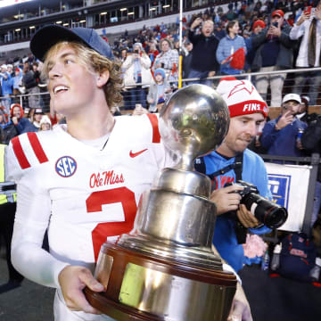 Nov 23, 2023; Starkville, Mississippi, USA; Mississippi Rebels quarterback Jaxson Dart (2) holds the Egg Bowl trophy after defeating the Mississippi State Bulldogs at Davis Wade Stadium at Scott Field. Mandatory Credit: Petre Thomas-USA TODAY Sports