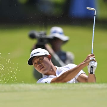 Collin Morikawa hits out of the bunker on the second hole