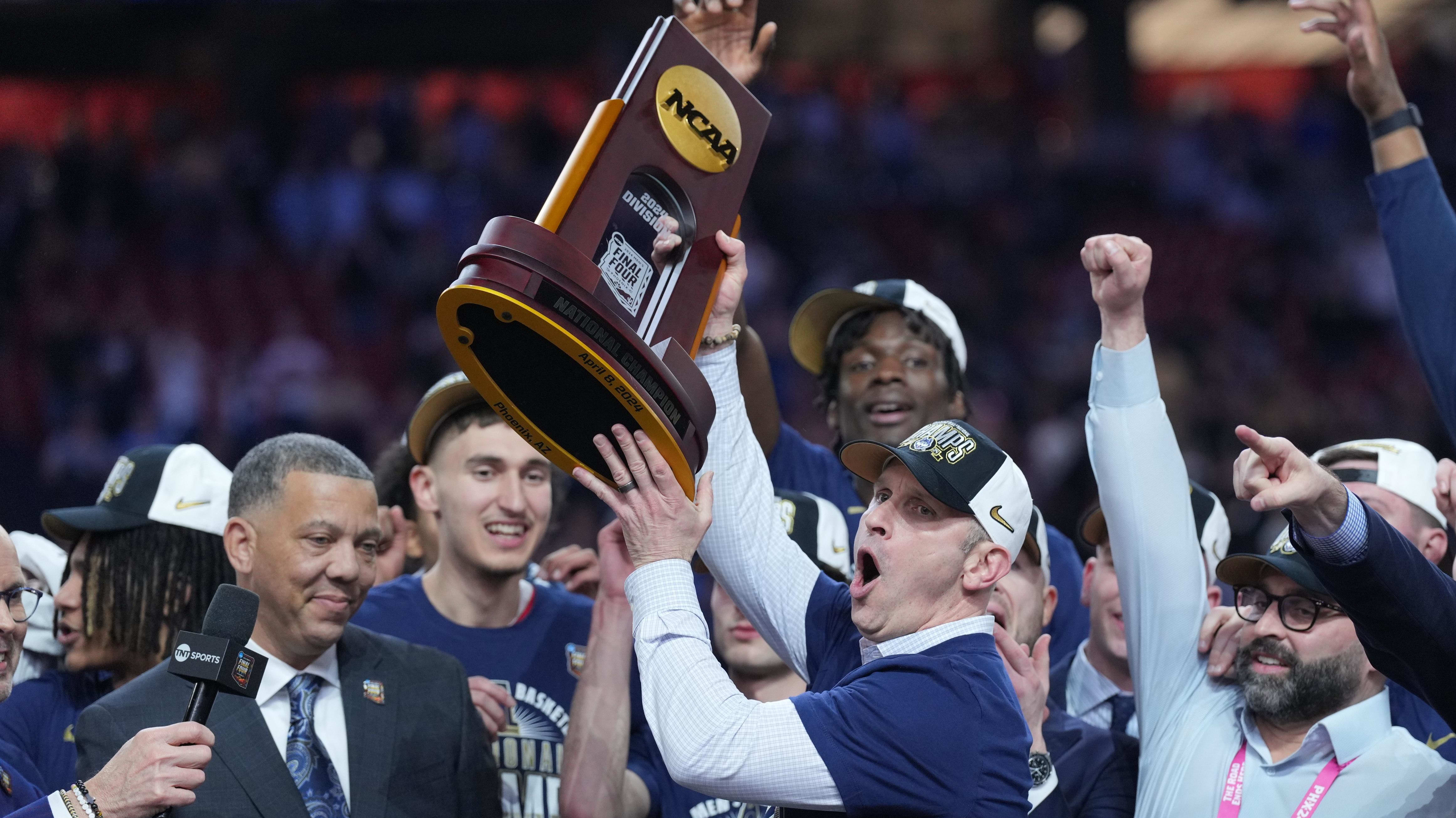 Connecticut Huskies head coach Dan Hurley hoists the championship trophy after winning the program's second straight national