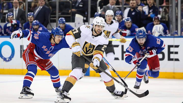 Feb 2, 2025; New York, New York, USA; Vegas Golden Knights defenseman Shea Theodore (27) skates through traffic with the puck as New York Rangers left wing Artemi Panarin (10) defends during the third period at Madison Square Garden. Mandatory Credit: Danny Wild-Imagn Images