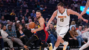 Golden State Warriors guard Stephen Curry dribbles past Denver Nuggets center Nikola Jokic.