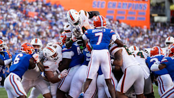 Aug 31, 2024; Gainesville, Florida, USA; Miami Hurricanes running back Mark Fletcher Jr. (4) jumps on the pile of defenders to score a touchdown against the Florida Gators during the second half at Ben Hill Griffin Stadium. Mandatory Credit: Matt Pendleton-Imagn Images