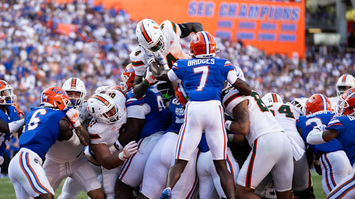 Aug 31, 2024; Gainesville, Florida, USA; Miami Hurricanes running back Mark Fletcher Jr. (4) jumps on the pile of defenders to score a touchdown against the Florida Gators during the second half at Ben Hill Griffin Stadium. Mandatory Credit: Matt Pendleton-Imagn Images