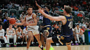 Feb 1, 2025; Coral Gables, Florida, USA; Miami Hurricanes guard Divine Ugochukwu (99) passes the basketball as Notre Dame Fighting Irish guard Markus Burton (3) and guard Matt Allocco (41) defend during the second half at Watsco Center. Mandatory Credit: Sam Navarro-Imagn Images