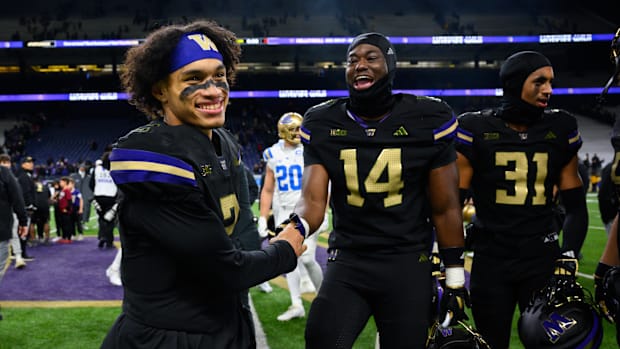 Washington Huskies quarterback Demond Williams Jr. (2) and edge rusher Milton Hopkins Jr. (14) celebrate after defeating the 