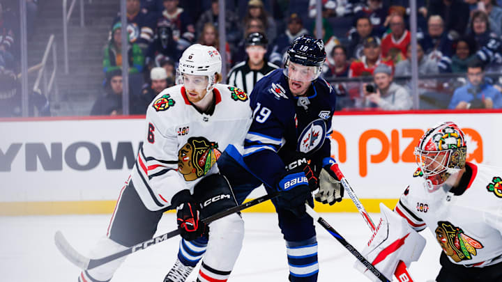 Oct 30, 2025; Winnipeg, Manitoba, CAN;  Winnipeg Jets forward Jonathan Toews (19) jostles for position with Chicago Blackhawks defenseman Sam Rinzel (6) during the second period at Canada Life Centre. Mandatory Credit: Terrence Lee-Imagn Images