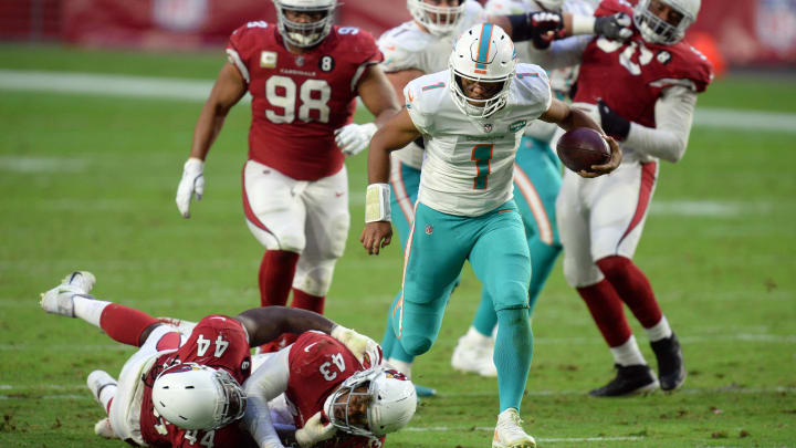 Miami Dolphins quarterback Tua Tagovailoa breaks the tackle of Arizona Cardinals linebacker Markus Golden (44) and Arizona Cardinals cornerback Byron Murphy (33) during the second half at State Farm Stadium during the 2020 season.