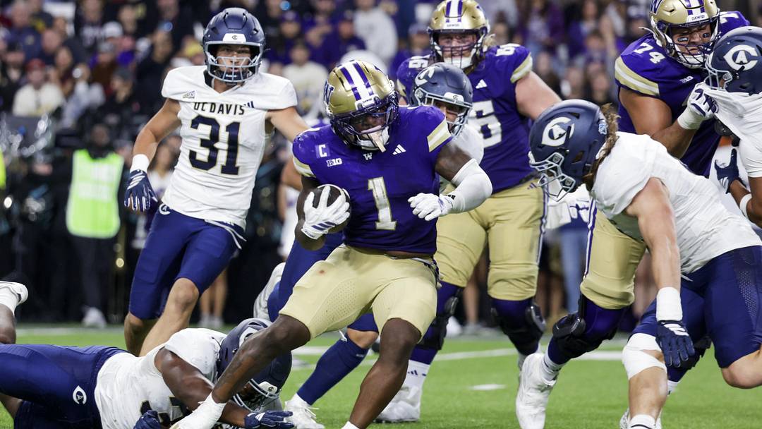 Sep 6, 2025; Seattle, Washington, USA; Washington Huskies running back Jonah Coleman (1) breaks a tackle attempt by UC Davis Aggies defensive lineman Derrell Porter (35) to rush for a touchdown during the second quarter at Husky Stadium. Mandatory Credit: Joe Nicholson-Imagn Images