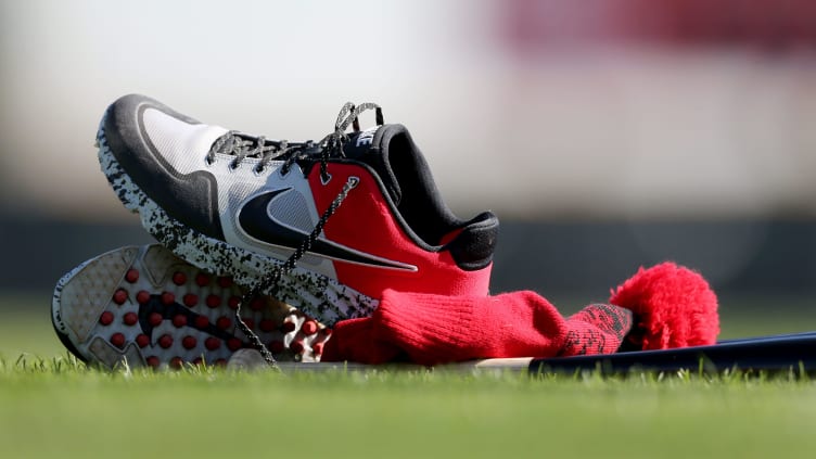 Cincinnati Reds shoes, bat and hat rest on the field during spring training