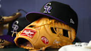 A detailed view of a Colorado Rockies hat and glove on the bench against the Atlanta Braves in the ninth inning at Truist Park.