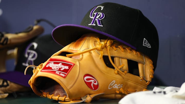 A detailed view of a Colorado Rockies hat and glove on the bench against the Atlanta Braves in the ninth inning at Truist Park.