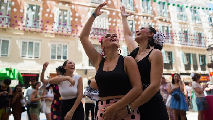 Women dressed in flamenco costumes are seen dancing at... Women dressed in flamenco costumes are seen dancing at...