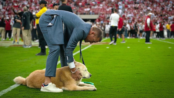 ESPN’s Kirk Herbstreit pets his dog Ben on the field before a game between the Georgia Bulldogs and Alabama Crimson Tide.