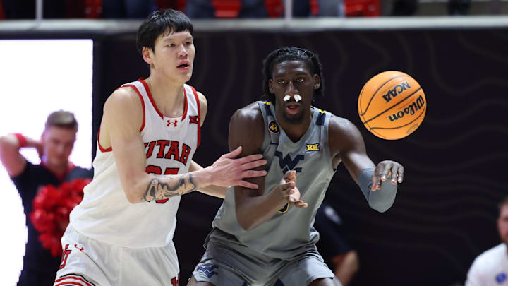 Mar 4, 2025; Salt Lake City, Utah, USA; West Virginia Mountaineers center Eduardo Andre (0) passes the ball away from Utah Utes guard Mike Sharavjamts (25) during the second half at Jon M. Huntsman Center. Mandatory Credit: Rob Gray-Imagn Images