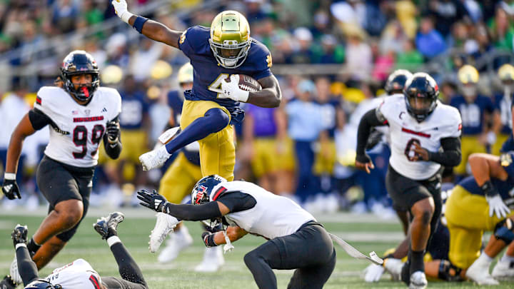 Sep 7, 2024; South Bend, Indiana, USA; Notre Dame Fighting Irish running back Jeremiyah Love (4) jumps over Northern Illinois Huskies safety Nate Valcarcel (9) in the third quarter at Notre Dame Stadium. 