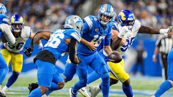 Detroit Lions quarterback Jared Goff (16) hands the ball to running back Jahmyr Gibbs (26).