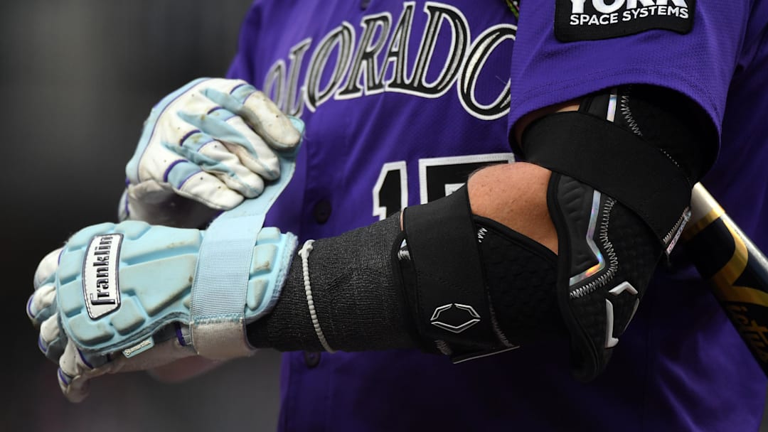 Sep 20, 2025; Denver, Colorado, USA; Colorado Rockies catcher Hunter Goodman (15) tightens the strap on a hand guard before his at bat during the first inning against the Los Angeles Angels at Coors Field. 
