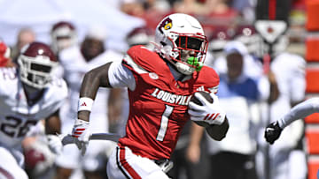Aug 30, 2025; Louisville, Kentucky, USA; Louisville Cardinals running back Isaac Brown (1) runs the ball against Eastern Kentucky Colonels defensive back Rishad Hence (21) during the first quarter at L&N Federal Credit Union Stadium. Mandatory Credit: Jamie Rhodes-Imagn Images