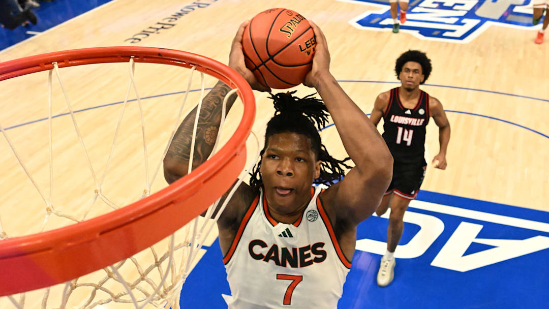 Mar 12, 2026; Charlotte, NC, USA; Miami (FL) Hurricanes forward Shelton Henderson (7) scores as Louisville Cardinals guard Adrian Wooley (14) defends in the second half at Spectrum Center. Mandatory Credit: Bob Donnan-Imagn Images