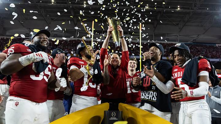 Jan 19, 2026; Miami Gardens, FL, USA; Indiana Hoosiers head coach Curt Cignetti hoists the trophy as he celebrates with defensive lineman Tyrique Tucker (95), wide receiver Elijah Sarratt (13), quarterback Fernando Mendoza (16), defensive lineman Mikail Kamara and defensive back D'Angelo Ponds (5) after defeating the Miami Hurricanes in the College Football Playoff National Championship game at Hard Rock Stadium. Mandatory Credit: Mark J. Rebilas-Imagn Images