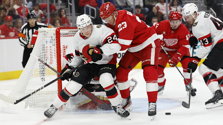 Oct 4, 2024; Detroit, Michigan, USA;  Ottawa Senators defenseman Jacob Bernard-Docker (24) and Detroit Red Wings left wing Lucas Raymond (23) battle for the puck in the second period at Little Caesars Arena. Mandatory Credit: Rick Osentoski-Imagn Images