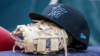 Apr 24, 2024; Atlanta, Georgia, USA; A detailed view of a Miami Marlins hat and glove in the dugout before a game against the Atlanta Braves at Truist Park. 