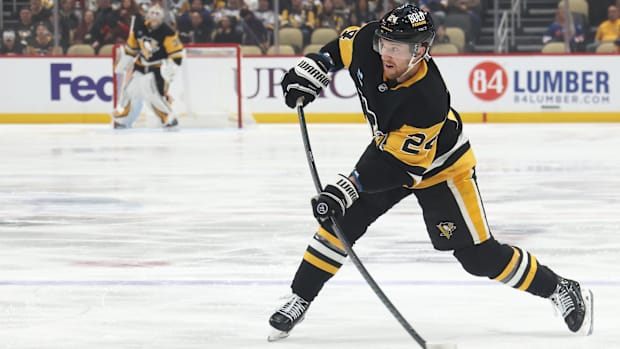 Hockey player in black uniform shoots the puck