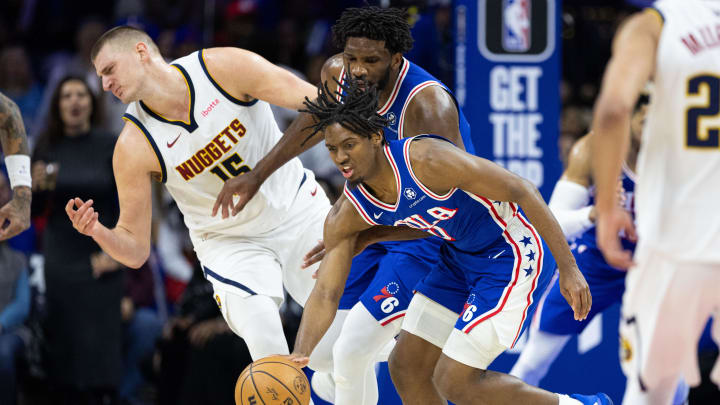 Jan 16, 2024; Philadelphia, Pennsylvania, USA; Philadelphia 76ers guard Tyrese Maxey (0) picks up a loose ball in front of center Joel Embiid (21) and Denver Nuggets center Nikola Jokic (15) during the third quarter at Wells Fargo Center. Mandatory Credit: Bill Streicher-USA TODAY Sports