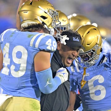 Nov 8, 2024; Pasadena, California, USA;   UCLA Bruins defensive coordinator Ikaika Malloe, center, celebrates with linebacker Carson Schwesinger (49) defensive back Jaylin Davies (6) after an interception in the second half against the Iowa Hawkeyes at the Rose Bowl. Mandatory Credit: Jayne Kamin-Oncea-Imagn Images