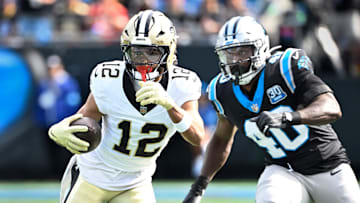 Nov 3, 2024; Charlotte, North Carolina, USA; New Orleans Saints wide receiver Chris Olave (12) with the ball as Carolina Panthers linebacker Charles Harris (40) defends in the first quarter at Bank of America Stadium. Mandatory Credit: Bob Donnan-Imagn Images
