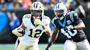Nov 3, 2024; Charlotte, North Carolina, USA; New Orleans Saints wide receiver Chris Olave (12) with the ball as Carolina Panthers linebacker Charles Harris (40) defends in the first quarter at Bank of America Stadium. Mandatory Credit: Bob Donnan-Imagn Images

