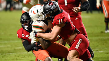 Nov 4, 2023; Raleigh, North Carolina, USA; Miami Hurricanes running back Mark Fletcher Jr. (22) is tackled by North Carolina State Wolfpack linebacker Payton Wilson (11) during the second half at Carter-Finley Stadium.  Mandatory Credit: Rob Kinnan-Imagn Images