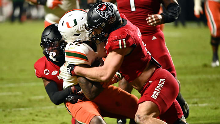Nov 4, 2023; Raleigh, North Carolina, USA; Miami Hurricanes running back Mark Fletcher Jr. (22) is tackled by North Carolina State Wolfpack linebacker Payton Wilson (11) during the second half at Carter-Finley Stadium.  Mandatory Credit: Rob Kinnan-Imagn Images