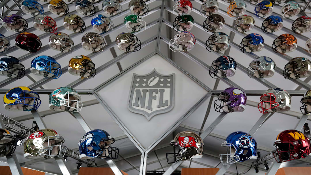A wall of team helmets on display in the gallery tent on the 2025 NFL Draft campus in Aswaubenon, Wis.