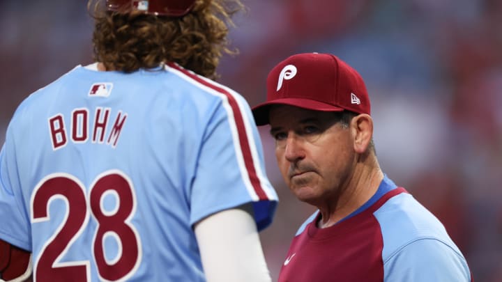 Aug 29, 2024; Philadelphia, Pennsylvania, USA; Philadelphia Phillies manager Rob Thomson (R) checks third base Alec Bohm (28) after an apparent injury during the first inning against the Atlanta Braves at Citizens Bank Park. 