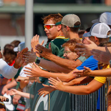 A young Green Bay Packers fan rides on the handlebars of his bicycle while riding to practice with Eric Wilson.