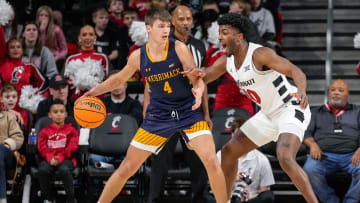 Cincinnati Bearcats guard Josh Reed (10) defends against Merrimack Warriors guard Jordan Derkack (4) in the first half of the NCAA basketball game between the Merrimack Warriors and the Cincinnati Bearcats at Fifth Third Arena in Cincinnati on Tuesday, Dec. 19, 2023.