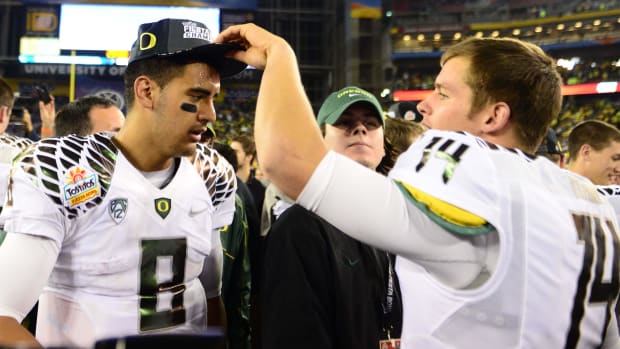 Oregon Ducks quarterback Marcus Mariota (8) gets a Fiesta Bowl champions hat from Dustin Haines (14) following the game.