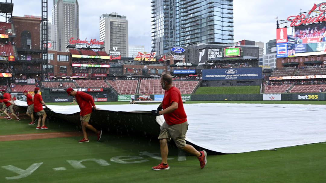 Jul 13, 2025; St. Louis, Missouri, USA;  St. Louis Cardinals grounds crew pulls the tarp on the field during a rain delay in the third inning of a game between the St. Louis Cardinals and the Atlanta Braves at Busch Stadium. Mandatory Credit: Jeff Curry-Imagn Images