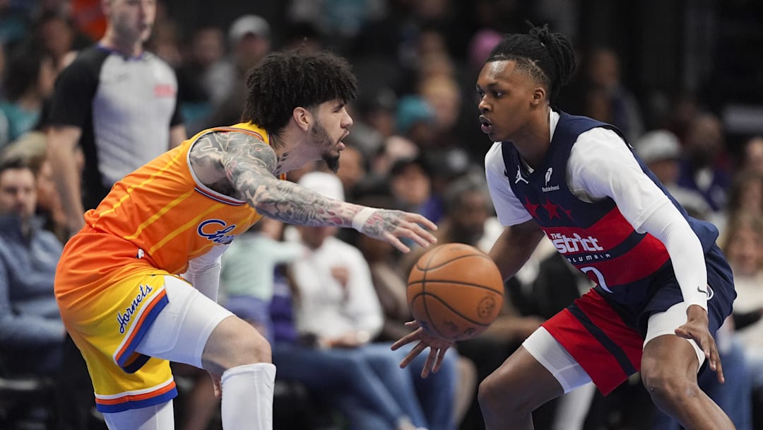 Jan 24, 2026; Charlotte, North Carolina, USA; Charlotte Hornets guard LaMelo Ball (1) passes the ball defended by Washington Wizards guard Bub Carrington (7) during the first quarter at the Spectrum Center. Mandatory Credit: Jim Dedmon-Imagn Images