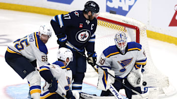 May 4, 2025; Winnipeg, Manitoba, CAN; St. Louis Blues goaltender Jordan Binnington (50) makes a save as Winnipeg Jets center Adam Lowry (17) looks for a rebound in the first overtime in game seven of the first round of the 2025 Stanley Cup Playoffs at Canada Life Centre. Mandatory Credit: James Carey Lauder-Imagn Images