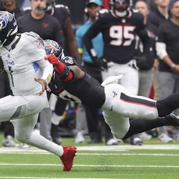Sep 28, 2025; Houston, Texas, USA; Tennessee Titans quarterback Cam Ward (1) runs with the ball as at Houston Texans linebacker Azeez Al-Shaair (0) attempts to make a tackle during the fourth quarter NRG Stadium. Mandatory Credit: Troy Taormina-Imagn Images